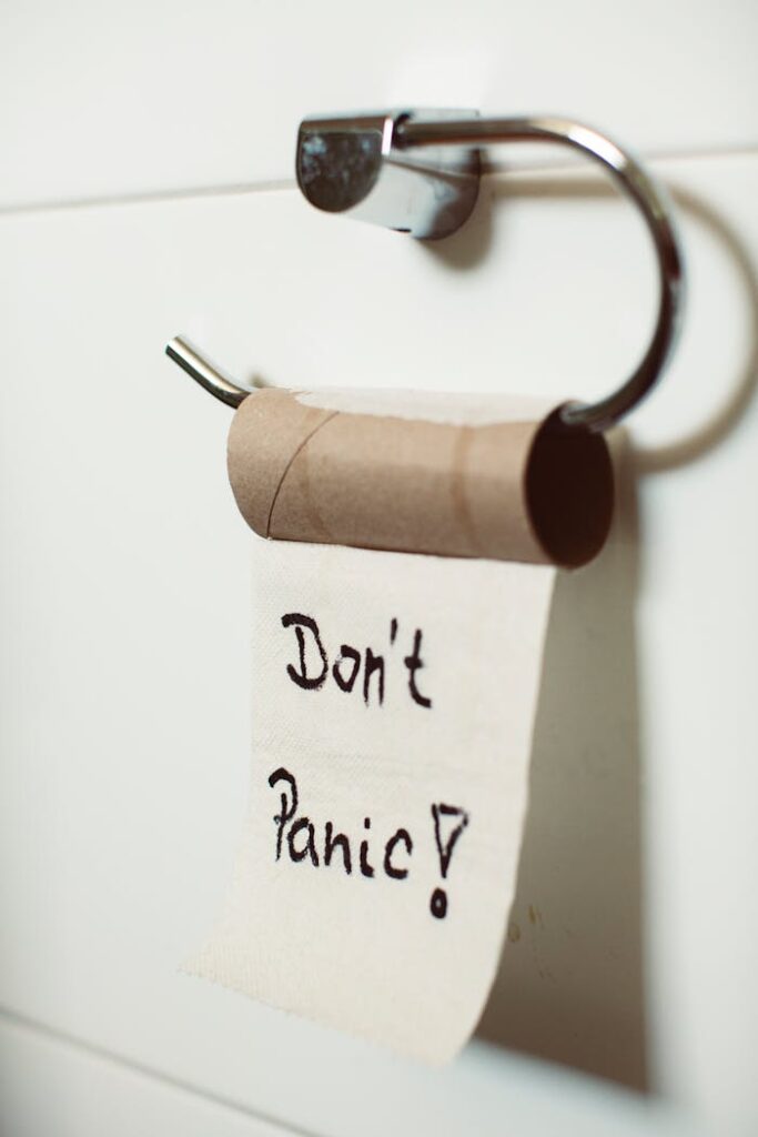 Close-up view of an empty toilet paper roll with a comforting "Don't Panic" message hanging on a holder.