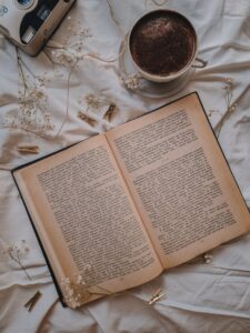 A serene flat lay featuring an open book, coffee, dried flowers, and clothespins.