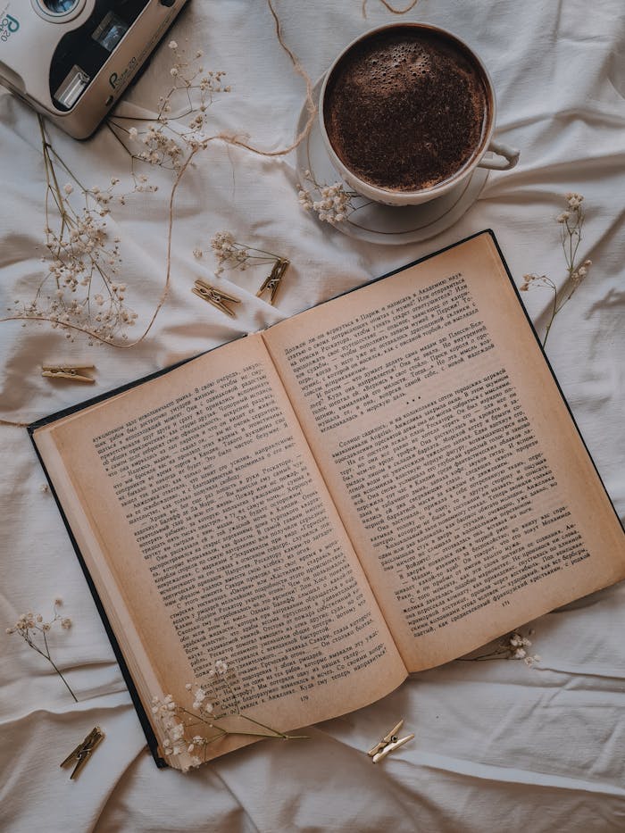 A serene flat lay featuring an open book, coffee, dried flowers, and clothespins.